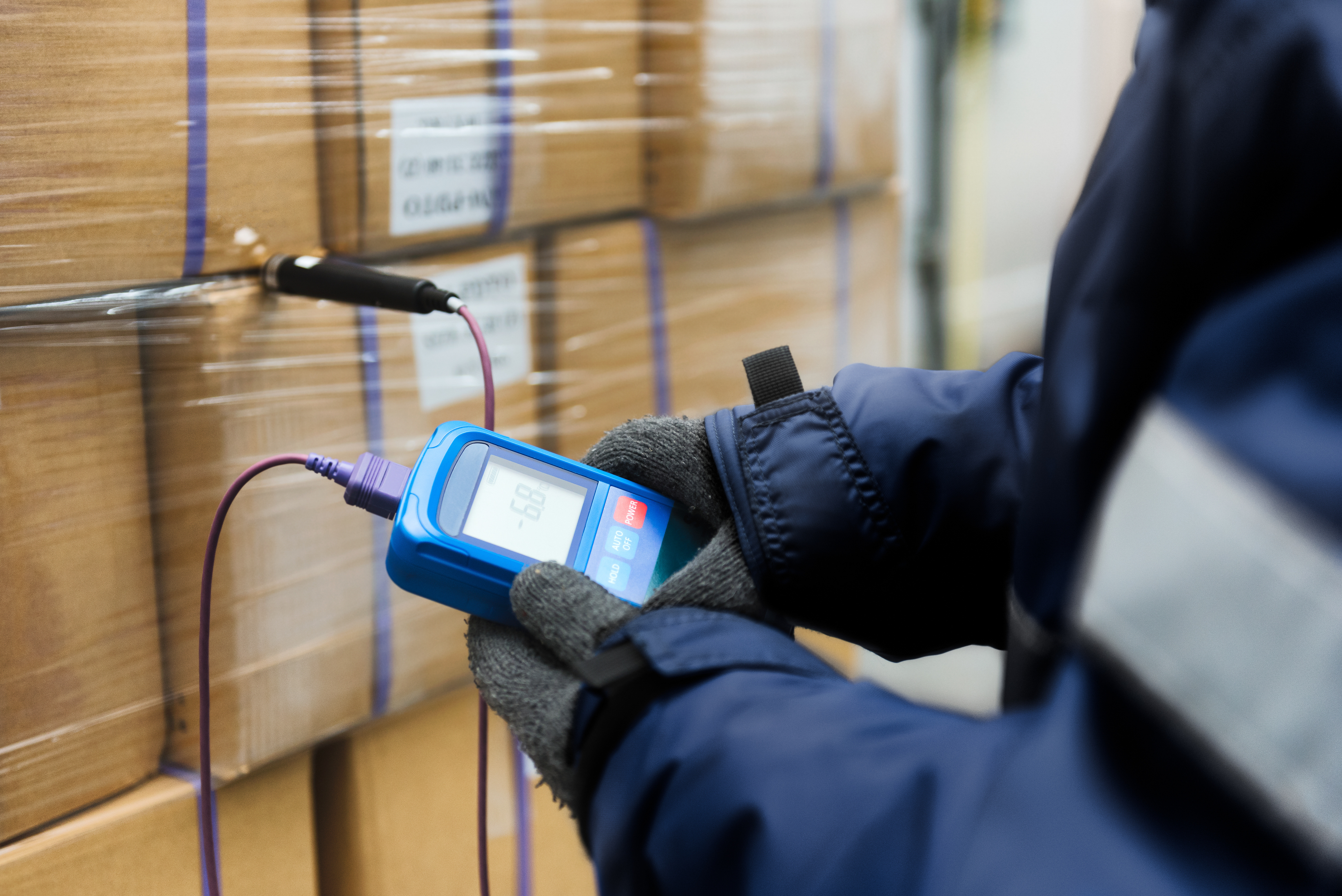 Hand of worker using thermometer to temperature measurement in the goods boxes with ready meals after import in the cold room or warehouse for keep temperature room content-image